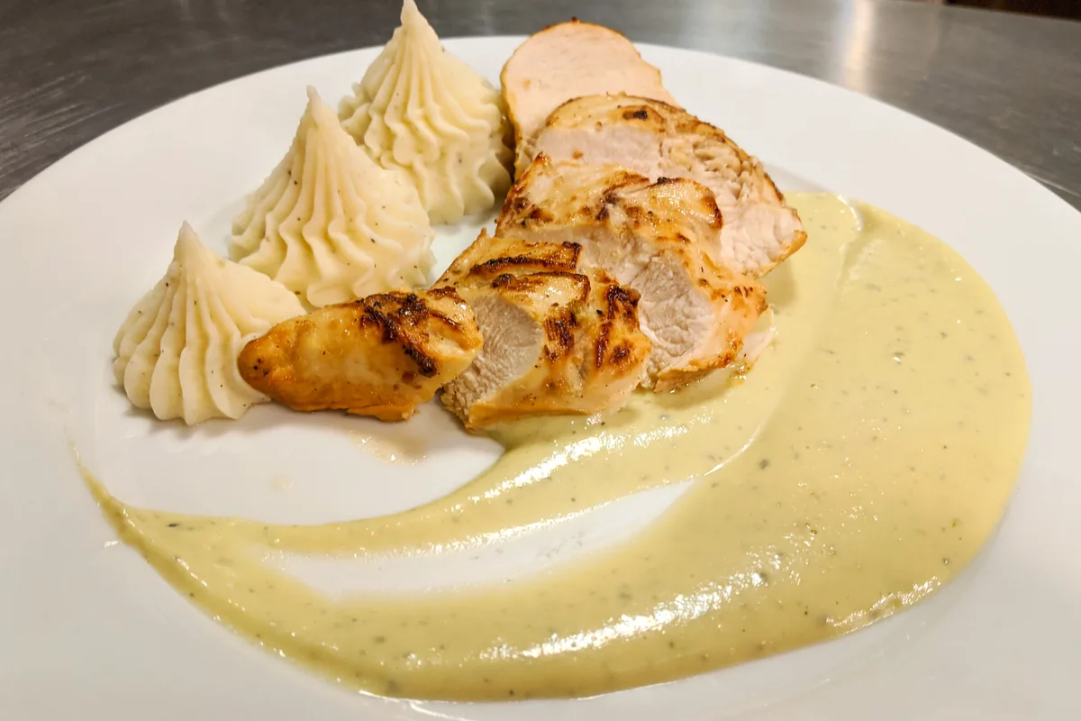 Chicken Steak with Blue Cheese Sauce Sliced Chicken Steak with Blue Cheese Sauce on a white plate with mashed potato quenelles.
