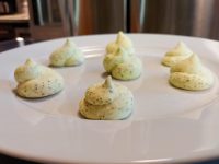 Herb Butter Seven piped mounds of pale green herb butter arranged on a white plate.