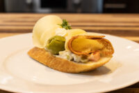Chlebíček slice topped with Vlašský Salát Vlašák, olive, curled cheese, and herb garnish on a white plate.