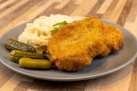 Dutch Schnitzel (Holandský Řízek) Golden breaded Dutch Schnitzel (Holandský Řízek) on a grey plate with mashed potato and pickles