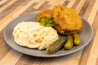 Dutch Schnitzel (Holandský Řízek) Two breaded fried Dutch Schnitzel (Holandský Řízek) cutlets with mashed potatoes, parsley, and pickles.