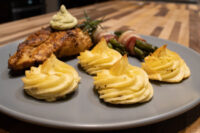 Rosemary Chicken Breasts Seared Rosemary Chicken Breasts with green herb sauce, rosemary sprig, potato swirls, and bacon-wrapped asparagus.