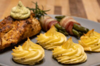 Rosemary Chicken Breasts Seared Rosemary Chicken Breasts topped with green sauce, served with potato swirls and bacon-wrapped asparagus.