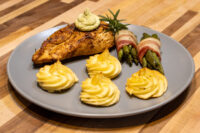 Rosemary Chicken Breasts Seared Rosemary Chicken Breast topped with herb butter, served with duchess potatoes and bacon-wrapped asparagus.