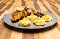 Rosemary Chicken Breasts Seared Rosemary Chicken Breast topped with green herb sauce, served with duchess potatoes and bacon-wrapped vegetables.