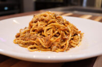 Spaghetti Bolognese Plated Spaghetti Bolognese with meat sauce and grated parmesan on a white oval dish.