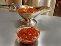 BBQ Sauce BBQ Sauce served in a small glass bowl and a metal gravy boat on a steel counter.