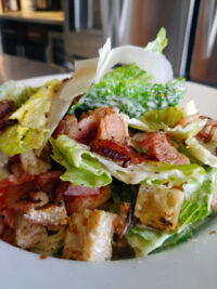 Caesar Salad Bowl of Caesar Salad with romaine, croutons, shaved parmesan, and crispy bacon pieces