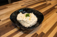 Cheese – Garlic Dip and Spread Creamy Cheese – Garlic Dip and Spread in a black bowl, garnished with herbs, on a wood counter.