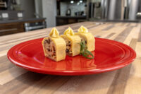 Sliced Cheese Roulade with Goat Cheese & Raisins showing golden exterior and dark speckled filling, on a red plate