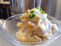 Chicken Salad Glass bowl of Chicken Salad with creamy dressing, diced chicken, pineapple chunks, and chopped chives on top