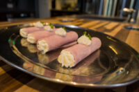 Creamy Horseradish Ham Rolls Six Creamy Horseradish Ham Rolls piped with cream filling and herb garnish on a metal platter