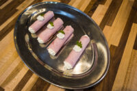 Creamy Horseradish Ham Rolls Four Creamy Horseradish Ham Rolls piped with white filling and topped with parsley on a silver platter.