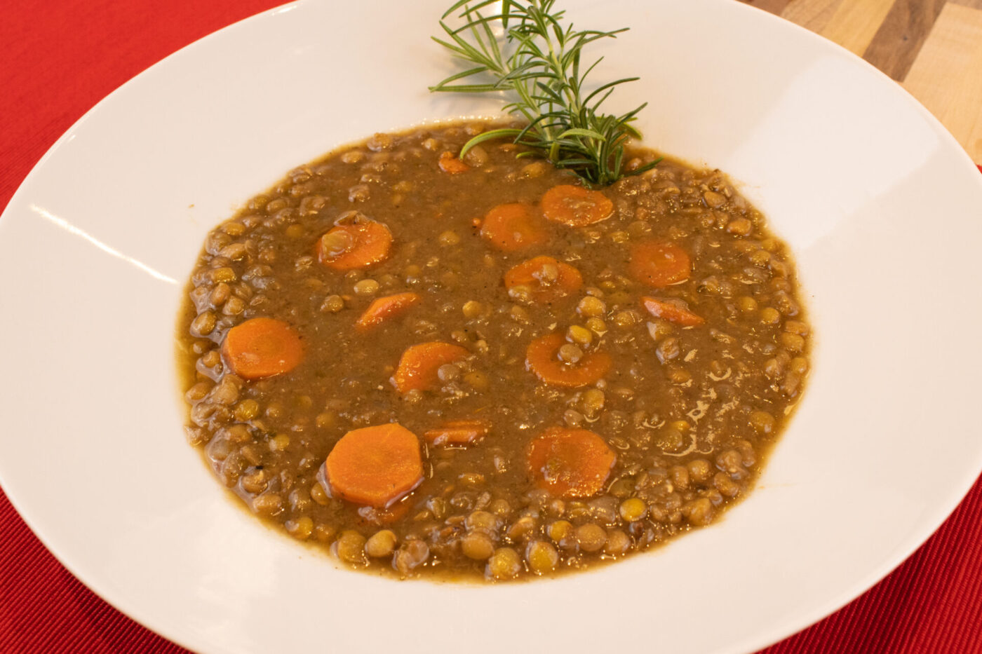 Bowl of Czech Lentil Soup Čočková Polévka with sliced carrots, garnished with a green herb sprig.