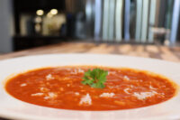 Czech Tomato Soup with Rice White bowl of Czech Tomato Soup with Rice topped with grated cheese and a parsley leaf.