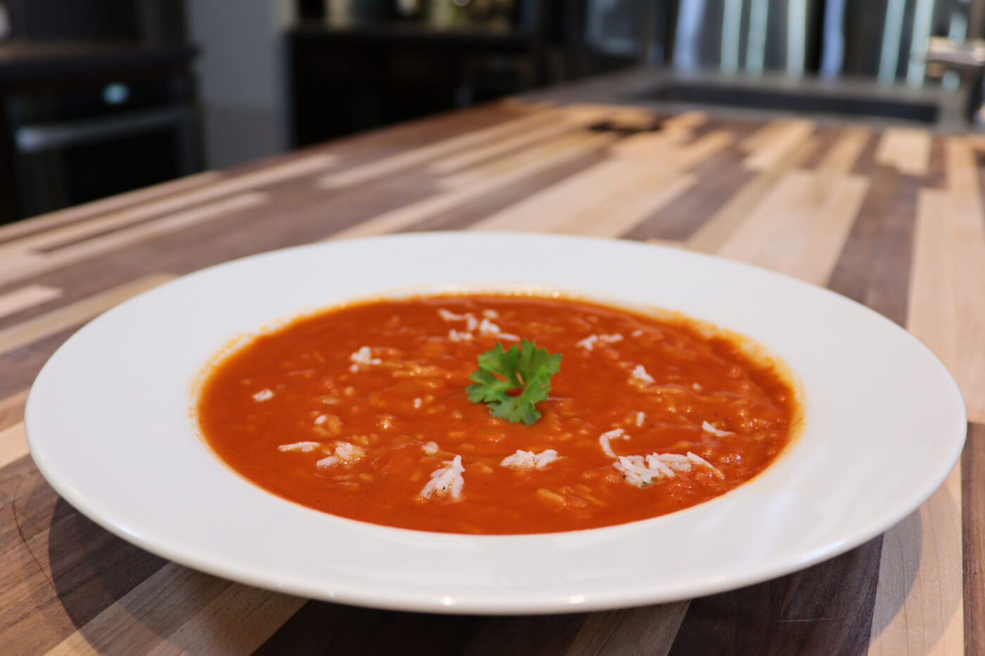 Czech Tomato Soup with Rice White bowl of Czech Tomato Soup with Rice topped with grated cheese and parsley, on a wood counter.