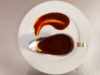 Demi-Glace Sauce (easy version) Dark reddish-brown Demi-Glace Sauce (easy version) swirled on a plate beside a filled gravy boat