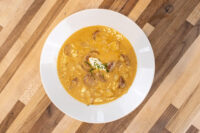 Bowl of Frankfurt Soup Frankfurtská Polévka with kielbasa slices, sour cream dollop, and chives on wood table