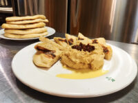 Hummus Whipped Hummus drizzled with olive oil and topped with a dark relish, served with grilled flatbread wedges.