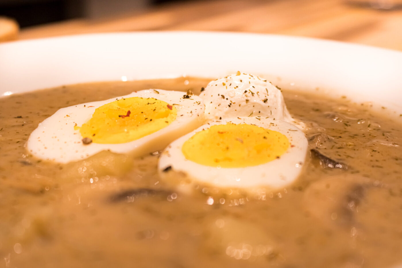 Bowl of Kulajda Soup topped with sliced hard-boiled eggs, dill, and cracked pepper.