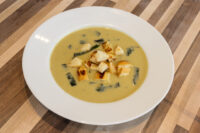 Leek Soup White bowl of pale green Leek Soup topped with golden croutons and thin leek strips on a wooden table