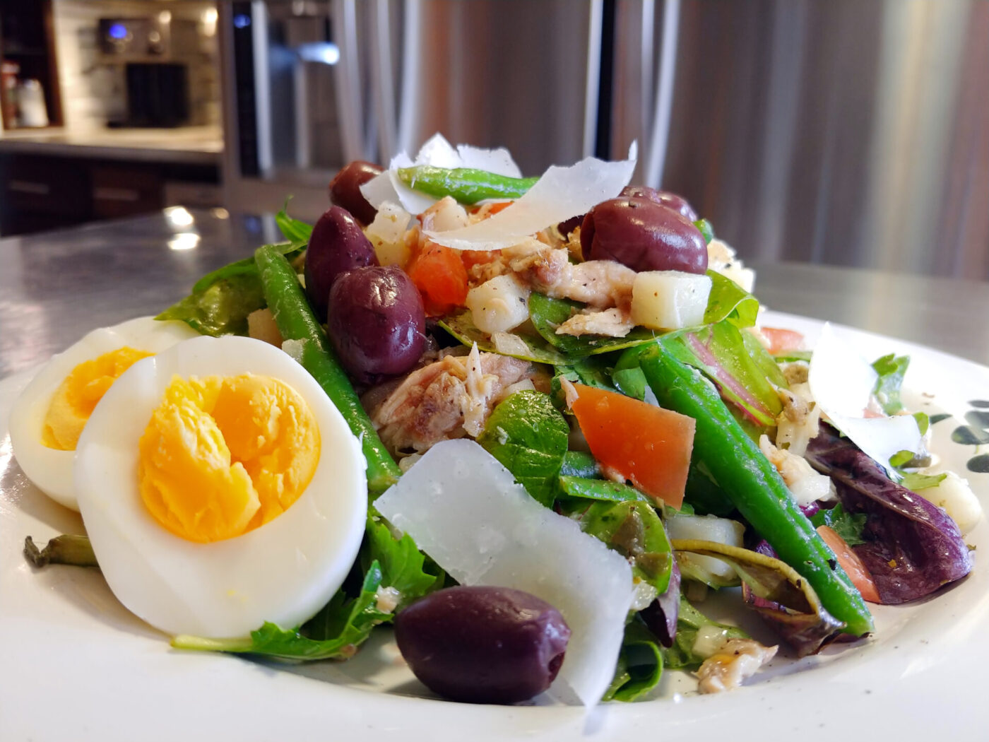 Niçoise Salad with Tuna Plated Niçoise Salad with Tuna showing halved eggs, olives, green beans, tomato, and shaved parmesan