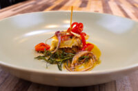Wedge of Pickled Brie Cheese Nakladany Hermelin in oil with onion curls and red pepper strips