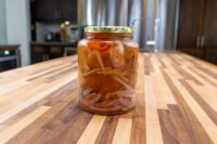 Pickled Sausage Utopenec Jar of Pickled Sausage Utopenec with onion slices, chili strips, and orange chunks in vinegar brine.