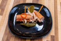 Pickled Sausage Utopenec Pickled Sausage Utopenec on a black plate with pickled onion, chili strips, and bay leaves