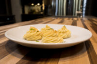 Five piped and baked Potato Kisses Bramborové Pusinky swirls on a white plate on a wooden table