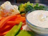 Ranch Dip Glass bowl of creamy herbed Ranch Dip surrounded by carrot sticks, broccoli, cauliflower, and snap peas.