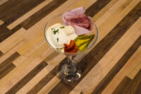 Russian Eggs (Ruské Vejce) Russian Eggs (Ruské Vejce) in a stemmed glass with egg salad scoops, ham, pickle, and herb garnish.