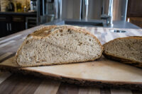 Czech Rye Bread Sliced loaf of Czech Rye Bread showing its crumb, on a wooden board in a kitchen.