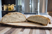 Czech Rye Bread Czech Rye Bread loaf sliced in half, showing speckled crumb, on a bark-edged wooden board.