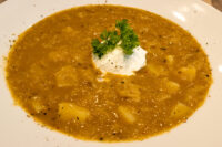 Czech Sauerkraut Soup Zelňačka Bowl of Czech Sauerkraut Soup Zelňačka with diced potatoes, sour cream dollop, and parsley garnish.