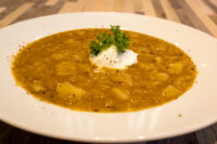 Czech Sauerkraut Soup Zelňačka Bowl of Czech Sauerkraut Soup Zelňačka with potato chunks, a sour cream dollop, and a parsley sprig on top