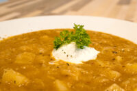 Czech Sauerkraut Soup Zelňačka Bowl of Czech Sauerkraut Soup Zelňačka with sour cream dollop and parsley garnish, potato chunks visible.