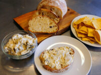 Artichoke Spinach Dip Artichoke Spinach Dip in a glass bowl, spread on bread, with sliced bread and tortilla chips.