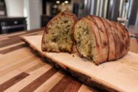 Twice-baked Herb Bread Sliced Twice-baked Herb Bread loaf on a wooden board, showing herb-flecked crumb and crisp crust.