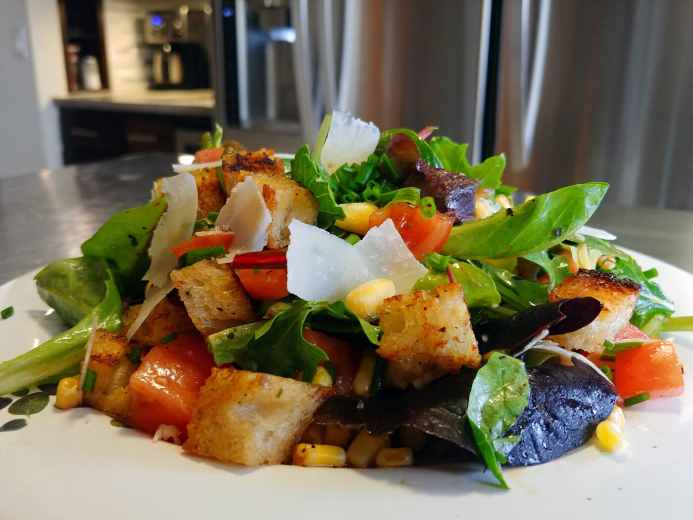 Vinaigrette Salad Plated Vinaigrette Salad with mixed greens, tomatoes, corn, croutons, and shaved cheese on a white plate.