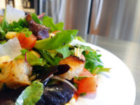 Vinaigrette Salad Close-up of Vinaigrette Salad with mixed greens, diced tomato, corn, shaved cheese, and croutons on a white plate