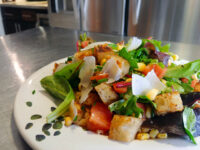 Vinaigrette Salad Vinaigrette Salad with mixed greens, tomatoes, corn, croutons, and shaved cheese on a white plate.