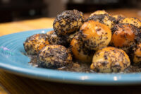 Bobalky with Poppyseeds and Honey: dough balls, some poppyseed-coated, others glazed, on a blue plate.