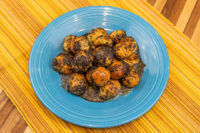 Bobalky with Poppyseeds and Honey: dough balls in dark honey, poppy-seed coated, on a blue plate.