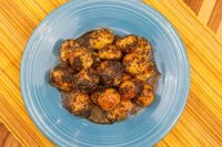 Golden dough balls coated in poppy seeds over dark honey on a blue plate, Bobalky with Poppyseeds and Honey.