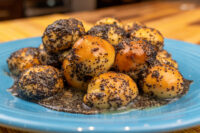 Bobalky with Poppyseeds and Honey piled on a blue plate, dough balls glazed and coated in poppy seeds.