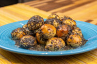Bobalky with Poppyseeds and Honey piled on a blue plate, glazed in syrup.
