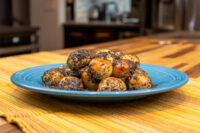 Pile of golden Bobalky with Poppyseeds and Honey coated in dark poppyseeds on a teal plate