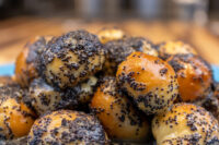Close-up pile of Bobalky with Poppyseeds and Honey, glossy dough balls coated in dark poppyseeds.