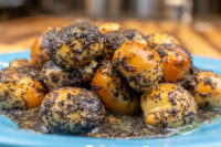Pile of Bobalky with Poppyseeds and Honey, poppy-seed coated dough balls glazed on a blue plate.